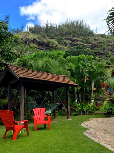 two red chairs and a gazebo in the grass at Kalani Hawaii Private Lodging in Pupukea