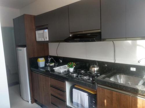 een keuken met een wastafel en een fornuis top oven bij Ap 203 - Mônaco Residence - rua na Beira da Praia - Não aceita pet in Florianópolis