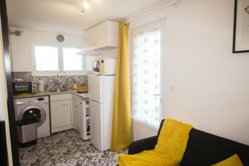 - une cuisine avec un réfrigérateur blanc et un rideau jaune dans l'établissement Maisonnette, à Flins-sur-Seine