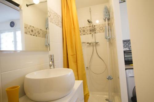 une salle de bain avec un lavabo blanc et une douche dans l'établissement Maisonnette, à Flins-sur-Seine