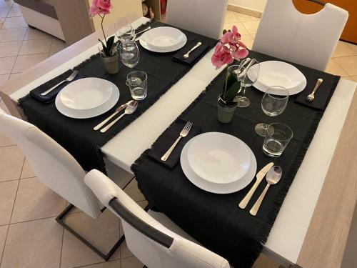 a table with plates and silverware on a black table cloth at AGM Suite Rome Airport FCO - Attico Parco Leonardo in Fiumicino