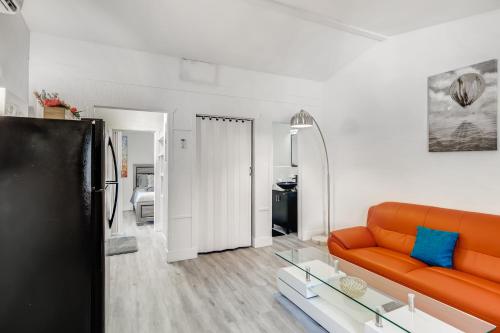 a living room with an orange couch and a glass table at Coral Sands 1br/1ba Close 2 Beach! in West Palm Beach