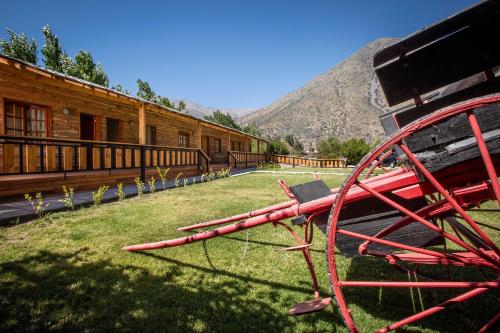 a red bench sitting in the grass next to a building at La Casa de Carlitos in San José de Maipo