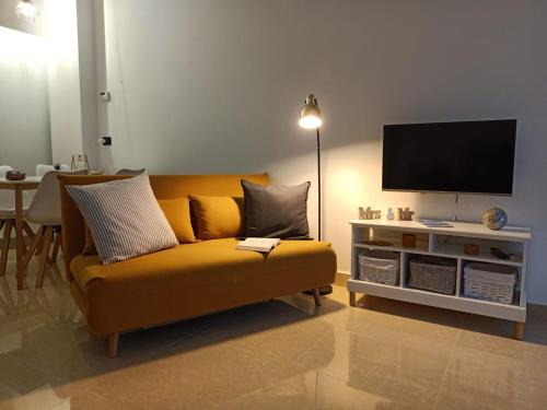 a living room with a yellow couch and a flat screen tv at L’angolo d’aMare in Lerici
