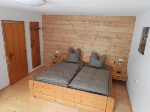 een bed in een kamer met een houten wand bij Achtalgarten in Pfronten
