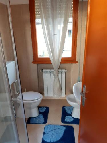 un bagno con due WC e una finestra con tappeti blu di Miniappartamento Singolo a Padova