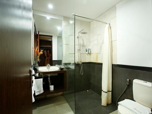 a bathroom with a shower and a toilet and a sink at Devata Suites and Residence in Legian