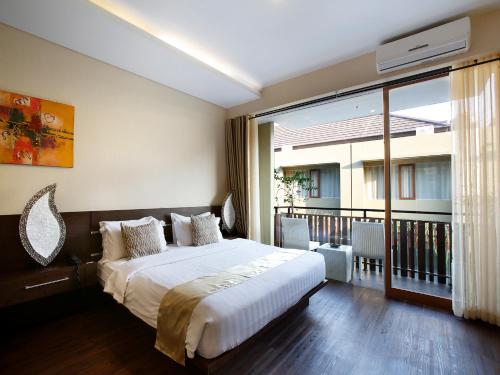a bedroom with a bed and a large window at Devata Suites and Residence in Legian