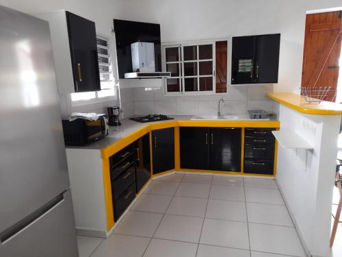 a kitchen with yellow and white counters and cabinets at Paradyse Den's près Sources d'Eau Chaudes , Paisible , Vue sur mer , WIFI in Bouillante
