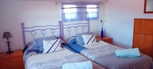 a bedroom with two beds with blue and white pillows at EL DESVÁN in Santa Marta de Tormes
