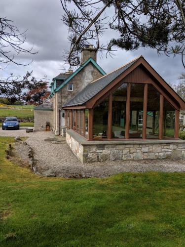 a house with a conservatory with glass windows at Auchencairn Cottage in Brora