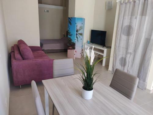 uma sala de estar com uma mesa e um sofá roxo em Appartamento via giansanti em Terracina