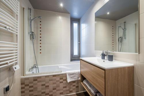 a bathroom with a sink and a tub and a mirror at Eden Hotel, Apartments and Chalet Chamonix Les Praz in Chamonix-Mont-Blanc