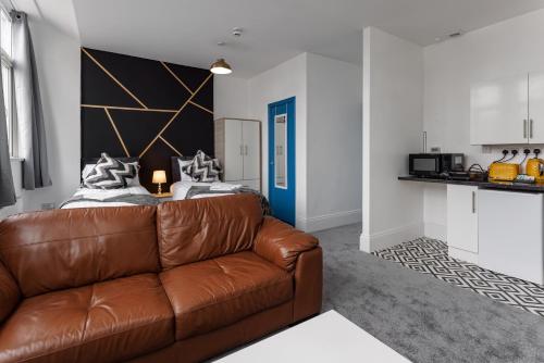 a living room with a brown couch and a kitchen at City Centre Studio 4 with Kitchenette, Free Wifi and Smart TV by Yoko Property in Middlesbrough