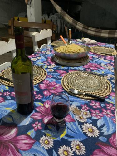 a table with a bottle of wine and a glass at Pousadinha da Lulu - Pontal Mangue Seco in Indiaroba