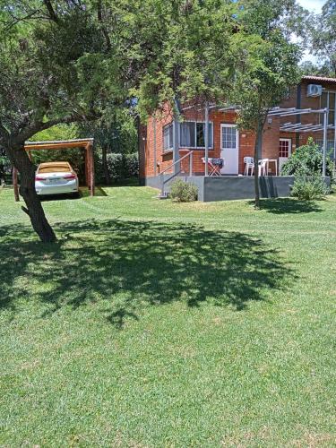 een schaduwrijke tuin met een boom en een huis bij al pie del morro in Merlo