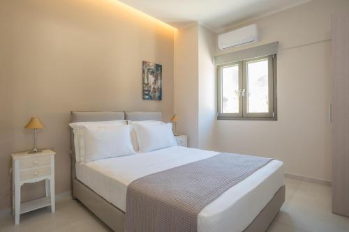 - une chambre avec un lit blanc et une fenêtre dans l'établissement Apollonian Luxury Apartments, à Vasiliki