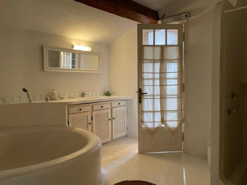 La salle de bains blanche est pourvue d'une baignoire et d'une porte. dans l'établissement MAS D ASTRE, à Maussane-les-Alpilles