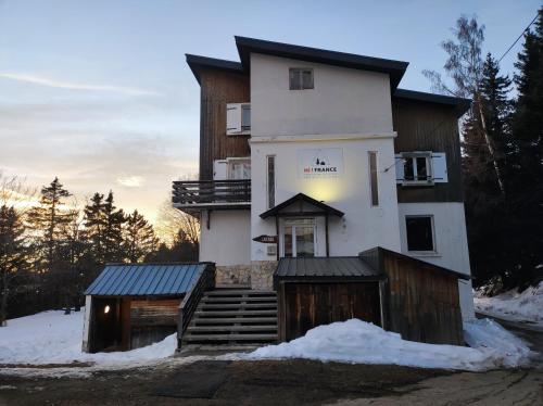 een groot wit gebouw met sneeuw op de grond bij Auberge de Jeunesse HI Chamrousse in Chamrousse