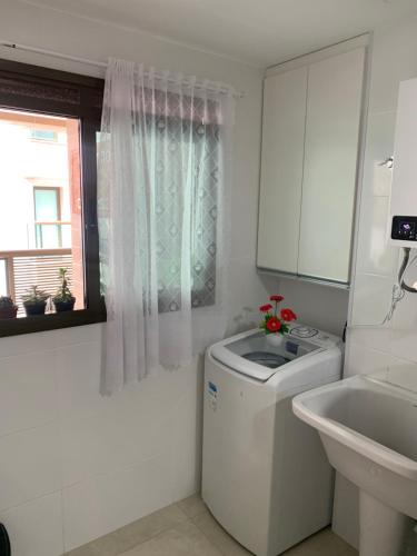 a white bathroom with a washing machine and a sink at apartamento de frente para o mar com linda area de lazer in Arraial do Cabo