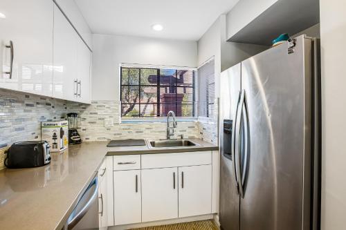 a kitchen with white cabinets and a stainless steel refrigerator at Casa de Oasis Permit# 549 in Palm Springs