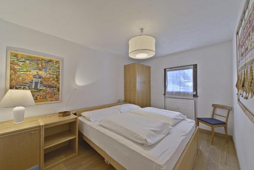 ein Schlafzimmer mit einem Bett und einem Schreibtisch mit einer Lampe in der Unterkunft Chesa Chavriol - Celerina in Celerina