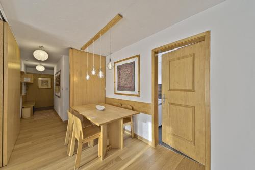 uma sala de jantar com uma mesa de madeira e uma porta em Chesa Chavriol - Celerina em Celerina