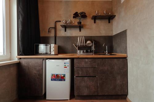 a small kitchen with a refrigerator and a counter at Квартира студия в центре Великий Гэтсби in Petropavlovsk