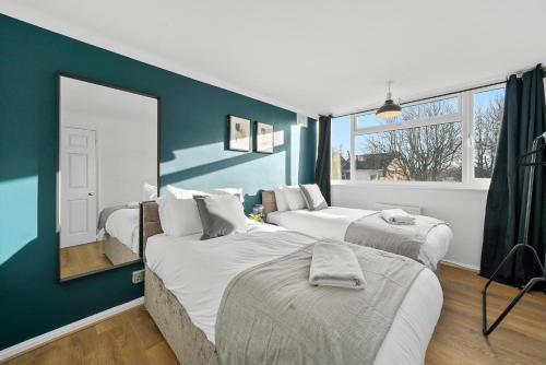 1 dormitorio con 2 camas y pared azul en Cosy 3 Bedroom with Free Parking, Garden and Smart TV with Netflix by Yoko Property en Coventry