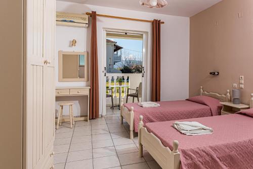 a room with two beds and a table with a mirror at Hotel Tassia for families & couples in Laganas