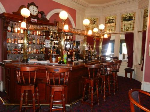 a bar in a pub with wooden bar stools at Morangie Hotel Tain in Tain