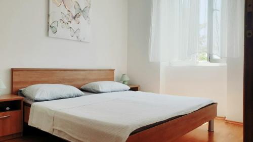 a bedroom with a bed with white sheets and a window at Apartmani Paron Šime in Seline