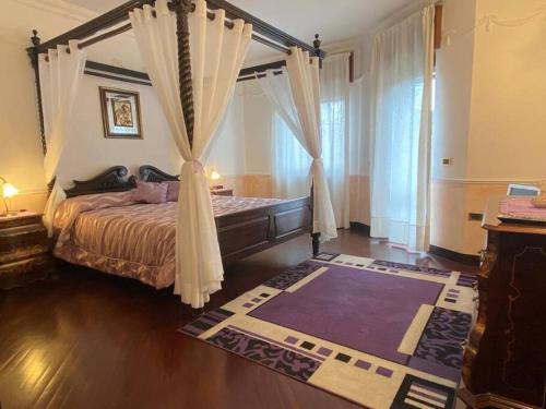 een slaapkamer met een hemelbed met gordijnen en een tapijt bij Casa vacanze parco dei fiori in Scafati