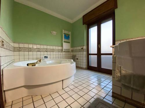 La salle de bains est pourvue d'une grande baignoire blanche et de murs verts. dans l'établissement Casa vacanze parco dei fiori, à Scafati