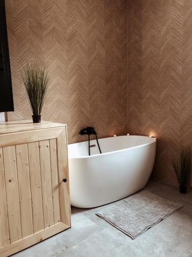 a white bath tub in a bathroom with a wooden wall at Jaszczurowa Apartament II in Jaszczurowa