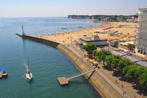 - une plage avec une jetée et un bateau dans l'eau dans l'établissement FLEUR DE SEL logement de 21m2 avec prêt vélos, meublé Tourisme 2 étoiles, cuisine et sdb privées avec terrasse clôturée de 17m2, à Batz-sur-Mer