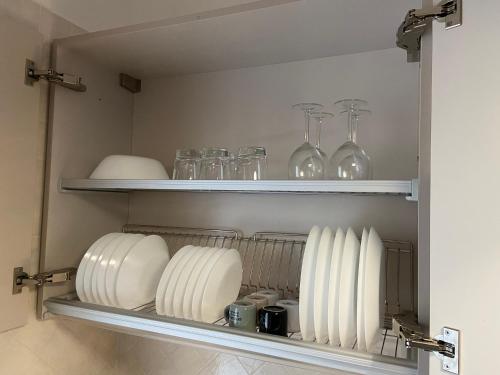 a shelf with plates and glasses on it at AGM Suite Rome Airport FCO - Attico Parco Leonardo in Fiumicino