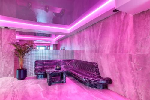 a pink room with a bench and a table at Hotel & Spa Biały Dom in Gliwice