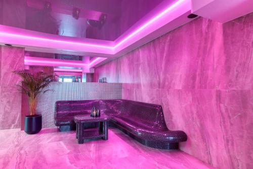 a pink room with a bench and a table at Hotel & Spa Biały Dom in Gliwice