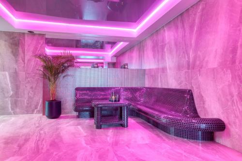 a pink room with a bench and a table at Hotel & Spa Biały Dom in Gliwice