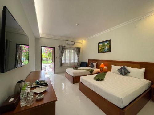 a hotel room with two beds and a desk and a room at Four Oceans Beach Resort - Bon Bien Mui Ne in Mui Ne