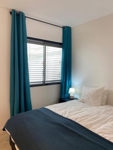 a bedroom with a bed with blue curtains and a window at PALMSEA Marbella-Estepona in Buenas Noches