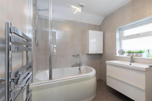 a bathroom with a bath tub and a sink at Modern Three Bedroom Gloucester Home in Gloucester