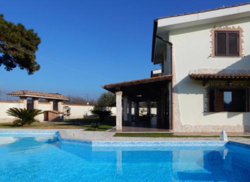 uma villa com piscina em frente a uma casa em Gold Luxury House em Anzio