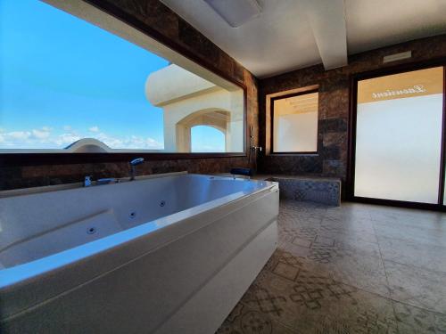 baño grande con bañera grande y ventana en Mahdia - Baghdadi - Laourient Apartments, restaurant, café, en Mahdia