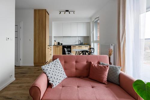 una sala de estar con un sofá rosa con almohadas. en Homewell Apartments Goplana en Poznan