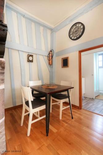 une table et des chaises dans une pièce avec une horloge au mur dans l'établissement Le Saint Georges, Centre historique proche gare, à Rennes