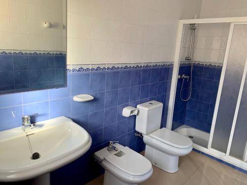 W wyłożonej niebieskimi kafelkami łazience znajduje się toaleta i umywalka. w obiekcie Chalet 5 dormitorios con piscina y jardín w mieście La Manga del Mar Menor