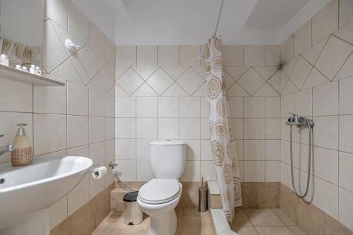 a bathroom with a toilet and a tub and a sink at Calma Home in Naxos Chora