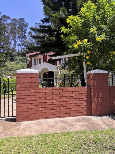 a brick retaining wall in front of a house at Narmada Holiday Home in Ooty